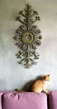 a cat sitting on top of a pink couch in front of a wall mounted clock