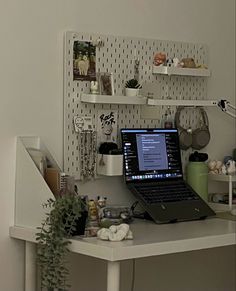 a laptop computer sitting on top of a white desk next to a potted plant