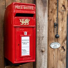 a red post box on the side of a wooden fence next to a mailbox