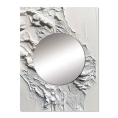 a round mirror mounted to the side of a white and silver wall hanging on a wall