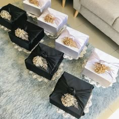 four boxes with gold decorations on them sitting on a blue rug in front of a couch