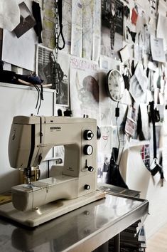 a white sewing machine sitting on top of a table next to a wall covered with pictures