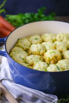 a blue pot filled with dumplings next to carrots