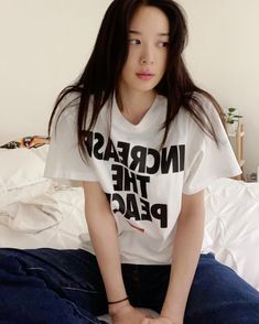 a woman sitting on top of a bed wearing a t - shirt that says increase the peace