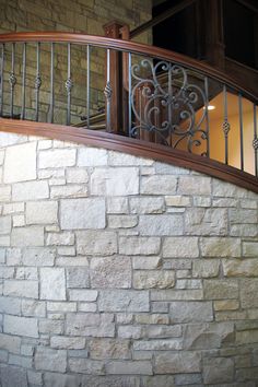 a stone wall with iron railings next to a spiral stair case in a building