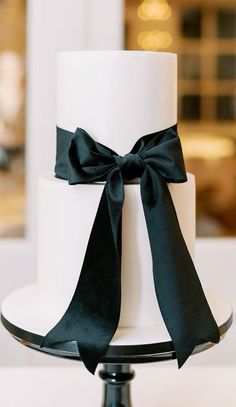 a white and black wedding cake with a bow on top