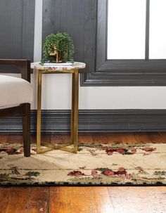 a small table with a potted plant sitting on it next to a chair in front of a window