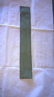 a tie is laying on top of a piece of white paper with green checkered fabric