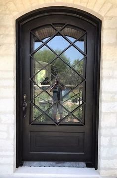 a man standing in front of a black door with a glass pane on it