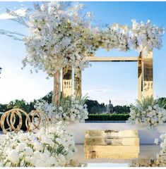 an outdoor wedding setup with white flowers and greenery on the ground, in front of a large mirror