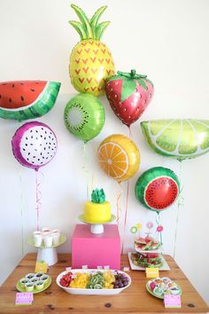 a table topped with lots of fruit and balloons