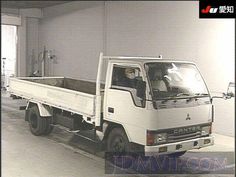 a white truck parked in a garage next to a wall with windows and doors on it