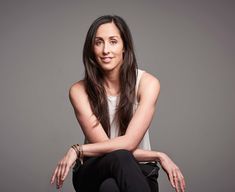 a woman sitting on the ground with her legs crossed and looking at the camera while smiling