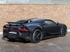 a black sports car parked in front of a brick wall