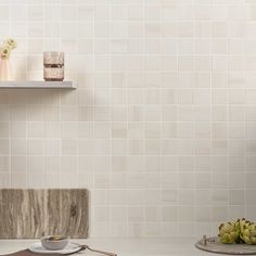 a white tiled wall with shelves and plates on it