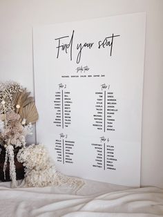 a table plan on a wall next to a bed with pillows and blankets in front of it