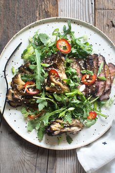 a white plate topped with meat and veggies on top of a wooden table