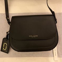 New With Tags, Perfect Condition Marc Jacobs Bag Classic Black Saddle Bag With Branded Hardware, Black Saddle Bag With Branded Hardware For Travel, Black Satchel Saddle Bag With Branded Hardware, Black Saddle Bag With Branded Hardware For Everyday Use, Modern Crossbody Saddle Bag With Dust Bag, Chic Black Saddle Bag For Shopping, Modern Black Saddle Bag With Branded Hardware, Black Saddle Bag With Detachable Strap For Shopping, Black Saddle Bag For Shopping