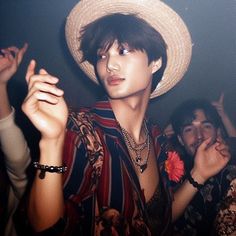 a young man wearing a white hat standing next to other people