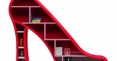 a red shoe shaped book shelf with books on it's bottom and shelves below