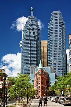 two people walking down the street in front of tall buildings