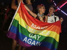 two people holding a gay pride flag at night