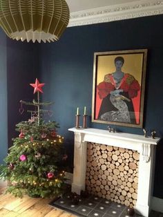 a decorated christmas tree sitting in front of a fire place next to a painting on the wall