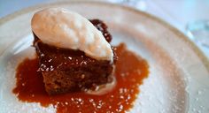 a piece of cake on a plate with ice cream and sauce in the middle, sitting on a table