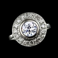 an antique diamond ring on a black background with the center stone surrounded by smaller round diamonds