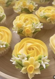 cupcakes decorated with yellow icing and flowers on a plate, ready to be eaten