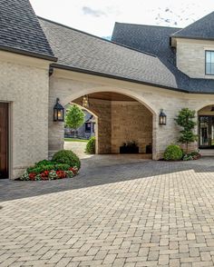 a large brick driveway in front of a house with two garages and an arched doorway