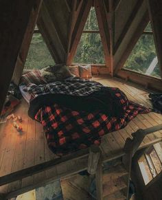 a bed in the middle of a room with wooden flooring and windows above it