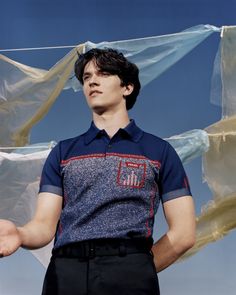 a young man is standing in front of some cloths on the clothes line and holding his hands out