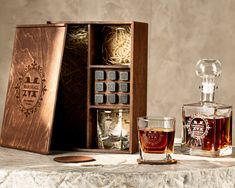 an assortment of liquor bottles and glasses sitting next to a wooden box on a table