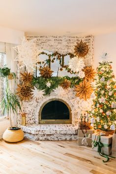 a living room decorated for christmas with white and gold decorations on the mantle, tree, and fireplace