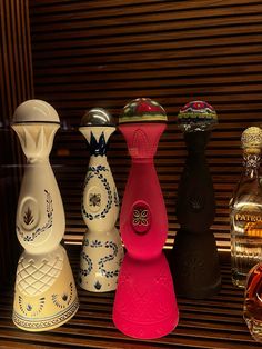 four different colored vases sitting on top of a shelf