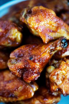 some chicken wings are piled on top of each other in a blue bowl, ready to be eaten