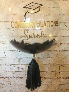 congratulations sign hanging on brick wall with tassels and graduation cap in the center