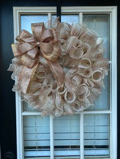 a wreath is hanging on the front door with ribbon around it and attached to an open window