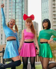 three young women dressed in colorful outfits posing for the camera with their arms up and legs crossed