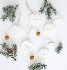 christmas ornaments with the word merry written on them and pine cones hanging from twine