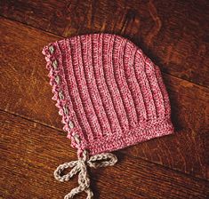 a pink knitted hat sitting on top of a wooden floor