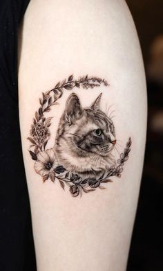 a cat tattoo on the left upper arm and lower arm, with leaves around it