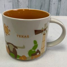 a close up of a coffee cup on a table with a wooden background and the words texas painted on it