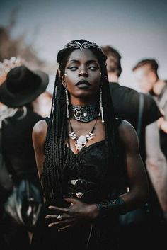 a woman with black makeup and braids standing in front of other people wearing hats