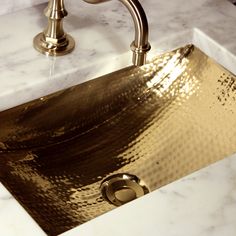 a gold sink in a bathroom with marble counter tops