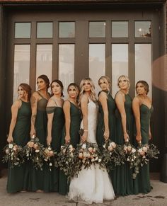 a group of women standing next to each other in front of a door wearing green dresses