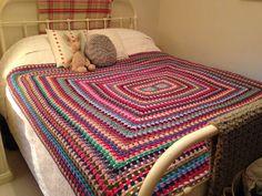 a crocheted blanket on top of a bed next to a teddy bear and pillow