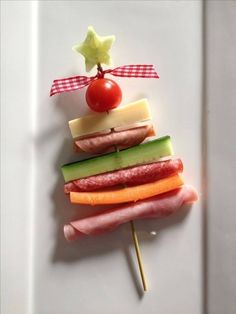 a christmas tree made out of veggies and meats on a stick with a cherry