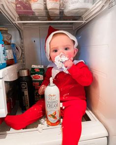 a baby sitting in an open refrigerator eating something